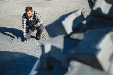 Eldivenli ellerle kum temel üzerine yerleştirerek bir kaldırım tuğla döşeme Oluşturucu.