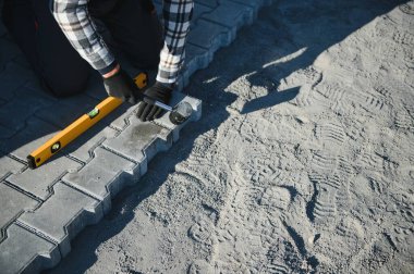 Eldivenli ellerle kum temel üzerine yerleştirerek bir kaldırım tuğla döşeme Oluşturucu.