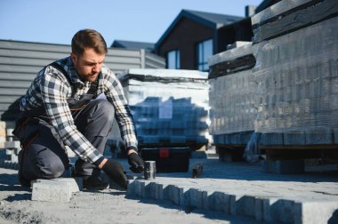 Eldivenli ellerle kum temel üzerine yerleştirerek bir kaldırım tuğla döşeme Oluşturucu.