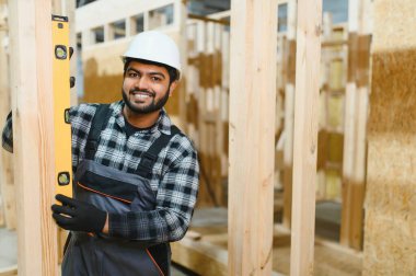 Modern modüler ev. Hintli işçi ahşap bir ev inşaatında çalışıyor..