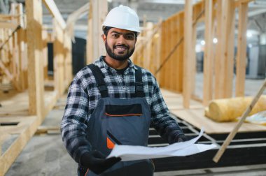 Modüler evlerin yapımı. Üniformalı ve inşaat alanında çalışan Hintli erkek inşaat işçisi..