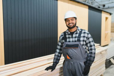 Modern modüler ev. Hintli işçi ahşap bir ev inşaatında çalışıyor..