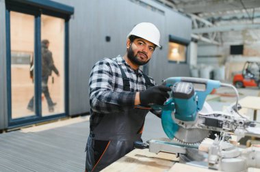 Hintli marangoz kereste fabrikalarında ahşap modüler evler inşa etmek için tahtalar kesiyor..