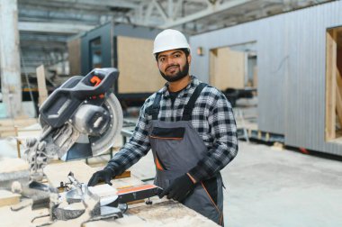 Hintli marangoz kereste fabrikalarında ahşap modüler evler inşa etmek için tahtalar kesiyor..