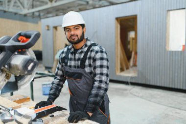 Hintli marangoz kereste fabrikalarında ahşap modüler evler inşa etmek için tahtalar kesiyor..
