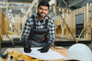 Modüler evlerin yapımı. İnşaat alanındaki Hintli mimar bir plana bakıyor..