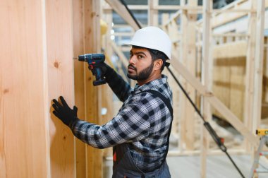 Modüler evlerin yapımı. Üniformalı ve inşaat alanında çalışan Hintli erkek inşaat işçisi..