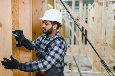 Modüler evlerin yapımı. Üniformalı ve inşaat alanında çalışan Hintli erkek inşaat işçisi..