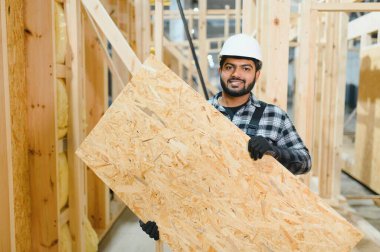 Modern modüler ev. Hintli işçi ahşap bir ev inşaatında çalışıyor..