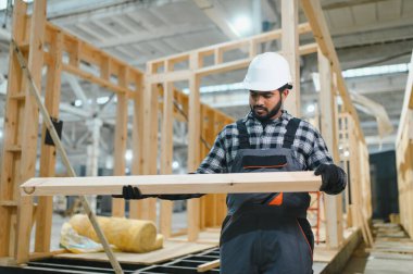 Modern modüler ev. Hintli işçi ahşap bir ev inşaatında çalışıyor..