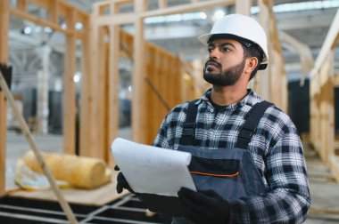 Modüler evlerin yapımı. Üniformalı ve inşaat alanında çalışan Hintli erkek inşaat işçisi..