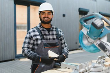 Hintli marangoz kereste fabrikalarında ahşap modüler evler inşa etmek için tahtalar kesiyor..