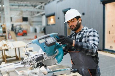 Hintli marangoz kereste fabrikalarında ahşap modüler evler inşa etmek için tahtalar kesiyor..