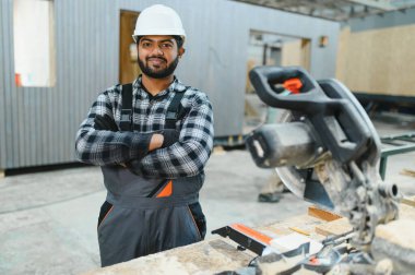 Hintli marangoz kereste fabrikalarında ahşap modüler evler inşa etmek için tahtalar kesiyor..