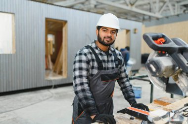 Hintli marangoz modüler evler inşaatında çalışıyor..