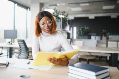 Afrika kökenli Amerikalı kız öğrenci, üniversitenin masasında okuyor. Yüksek öğrenim kavramı.