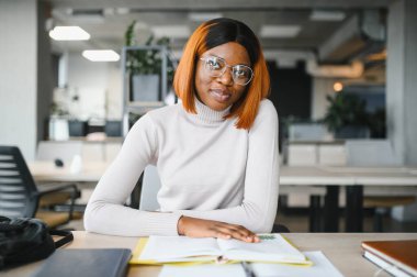 Afrika kökenli Amerikalı kız öğrenci, üniversitenin masasında okuyor. Yüksek öğrenim kavramı.