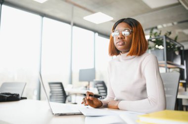 Genç Afrikalı Amerikalı öğrenci üniversitede okuyor, araştırma gazetesinde çalışıyor, açık kitaplarla masada oturuyor..