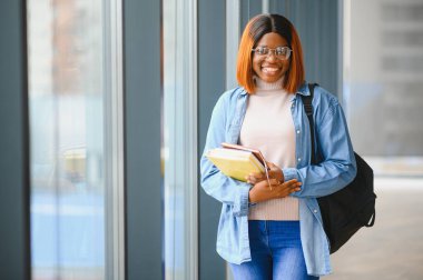 Modern bir üniversitenin koridorunda Afro-Amerikalı bir kız öğrencinin portresi. Yüksek öğrenim kavramı