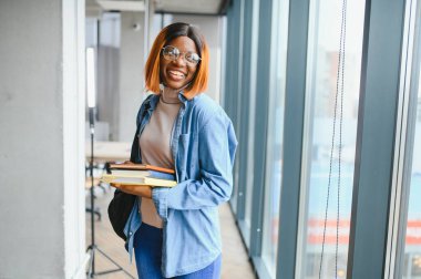Modern bir üniversitenin koridorunda Afro-Amerikalı bir kız öğrencinin portresi. Yüksek öğrenim kavramı