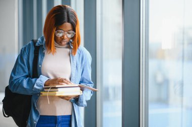 Modern bir üniversitenin koridorunda Afro-Amerikalı bir kız öğrencinin portresi. Yüksek öğrenim kavramı
