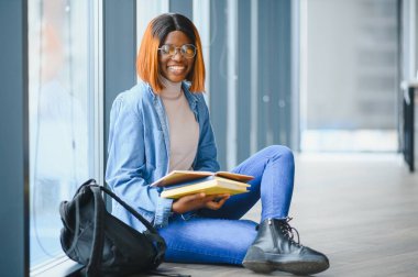 Modern bir üniversitenin koridorunda Afro-Amerikalı bir kız öğrencinin portresi. Yüksek öğrenim kavramı