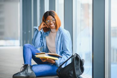 Modern bir üniversitenin koridorunda Afro-Amerikalı bir kız öğrencinin portresi. Yüksek öğrenim kavramı