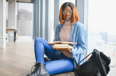 Modern bir üniversitenin koridorunda Afro-Amerikalı bir kız öğrencinin portresi. Yüksek öğrenim kavramı