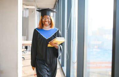 Mezuniyet töreninde diploması olan mutlu Afrikalı Amerikalı kız öğrenci..