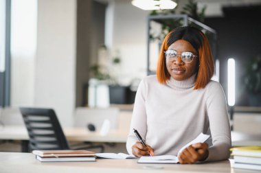 Afrika kökenli Amerikalı kız öğrenci, üniversitenin masasında okuyor. Yüksek öğrenim kavramı.