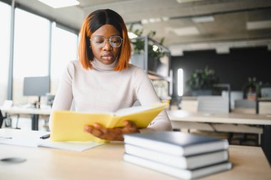 Afrika kökenli Amerikalı kız öğrenci, üniversitenin masasında okuyor. Yüksek öğrenim kavramı.