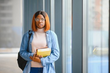 Modern bir üniversitenin koridorunda Afro-Amerikalı bir kız öğrencinin portresi. Yüksek öğrenim kavramı