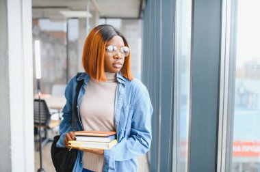 Modern bir üniversitenin koridorunda Afro-Amerikalı bir kız öğrencinin portresi. Yüksek öğrenim kavramı