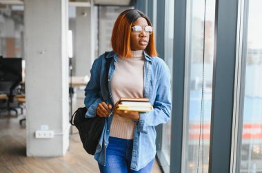 Üniversite koridorunda elinde kitaplarla bekleyen Afrikalı Amerikalı öğrenci..