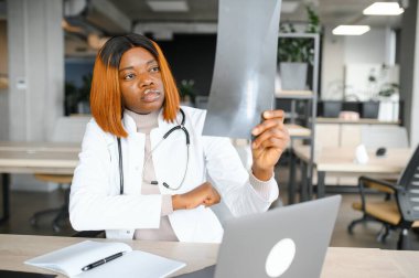 Hastanede göğüs röntgenlerini inceleyen hemşire. Whitecoat 'ta çalışan genç ve ciddi bir radyolog hasta akciğerlerinin röntgenini çekerken bilgisayar monitörüyle birlikte iş yerinde oturuyor..