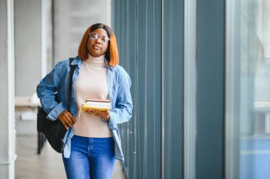 Modern bir üniversitenin koridorunda Afro-Amerikalı bir kız öğrencinin portresi. Yüksek öğrenim kavramı