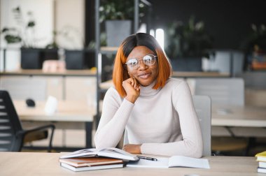 Afrika kökenli Amerikalı kız öğrenci, üniversitenin masasında okuyor. Yüksek öğrenim kavramı.