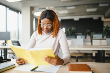 Sınıfta okuyan, üniversite ödevi üzerinde çalışan ciddi bir Afrikalı Amerikalı kız öğrenciye odaklanmış..