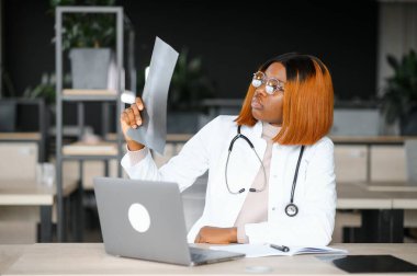 Doktor röntgen çekiyor. Ofisteki genç Afro-Amerikalı doktor röntgene bakıyor..