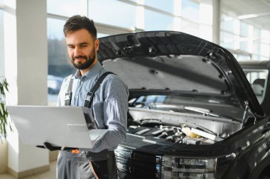 Otomotiv teknisyeni bilgisayarda tanılama yazılımı çalıştırıyor. Tamirci oto servis garajında araç tanılama testi yapıyor..