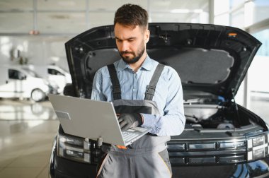 Tamirci Artırılmış Gerçeklik Tanılama Yazılımlı Bilgisayar Kullanıyor. Uzman Uzman Aracın Motorunu Kırık Parçaları Belirlemek İçin Denetliyor. Birinci sınıf araba servisi..