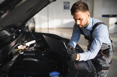 Tamirci Artırılmış Gerçeklik Tanılama Yazılımlı Bilgisayar Kullanıyor. Uzman Uzman Aracın Motorunu Kırık Parçaları Belirlemek İçin Denetliyor. Birinci sınıf araba servisi..
