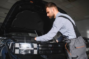 Tamirci Artırılmış Gerçeklik Tanılama Yazılımlı Bilgisayar Kullanıyor. Uzman Uzman Aracın Motorunu Kırık Parçaları Belirlemek İçin Denetliyor. Birinci sınıf araba servisi..