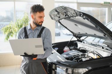 Tamirci Artırılmış Gerçeklik Tanılama Yazılımlı Bilgisayar Kullanıyor. Uzman Uzman Aracın Motorunu Kırık Parçaları Belirlemek İçin Denetliyor. Birinci sınıf araba servisi..