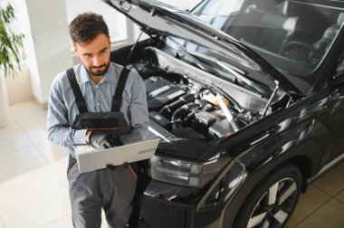 Tamirci Artırılmış Gerçeklik Tanılama Yazılımlı Bilgisayar Kullanıyor. Uzman Uzman Aracın Motorunu Kırık Parçaları Belirlemek İçin Denetliyor. Birinci sınıf araba servisi..