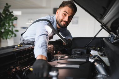 Modern araba tamirhanesinde arabalı dost canlısı bir tamirci. Profesyonel teknisyen araç kontrolü ve bakımını kontrol ediyor. Otomotiv endüstrisi ve müşteri hizmetleri kavramı.