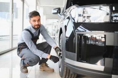 Tamirci garajda çalışıyor ve tekerlek alaşımı değiştiriyor. Tamir ya da bakım servisi. Kış ve yaz lastiklerinin değiştirilmesi.