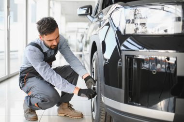 Tamirci garajda çalışıyor ve tekerlek alaşımı değiştiriyor. Tamir ya da bakım servisi. Kış ve yaz lastiklerinin değiştirilmesi.