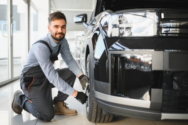 Tamirci garajda çalışıyor ve tekerlek alaşımı değiştiriyor. Tamir ya da bakım servisi. Kış ve yaz lastiklerinin değiştirilmesi.
