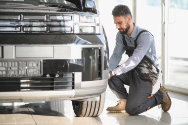 Tamirci garajda çalışıyor ve tekerlek alaşımı değiştiriyor. Tamir ya da bakım servisi. Kış ve yaz lastiklerinin değiştirilmesi.